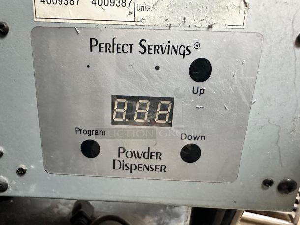 Digital display and controls of a Perfect Servings powder dispenser showing numeric reading. Panel with control buttons labeled Up, Down, and Program.