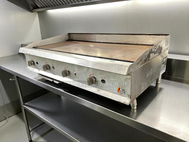 Cooking Performance Group GM-CPG-48-NL 48" gas griddle, manual controls, stainless steel, visible wear, four control knobs.