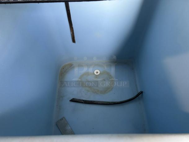 Interior view of Ice-O-Matic CIM1136HA ice machine showing base with residue and hose, indicating previously used condition.