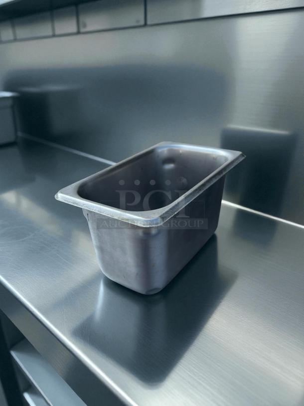 Stainless steel 1/9 size, 4" deep hotel pan in great condition, shown on a metal kitchen surface.