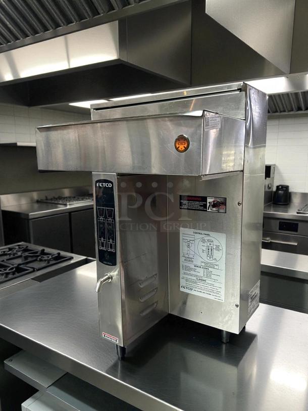 Fetco CBS-2032e coffee brewer in excellent condition on stainless steel table, clear control panel instructions.