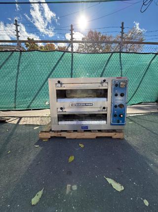 Bakers Pride EP-2-2828 double deck electric pizza oven on pallet, stainless steel, visible control panel, outdoor setting.