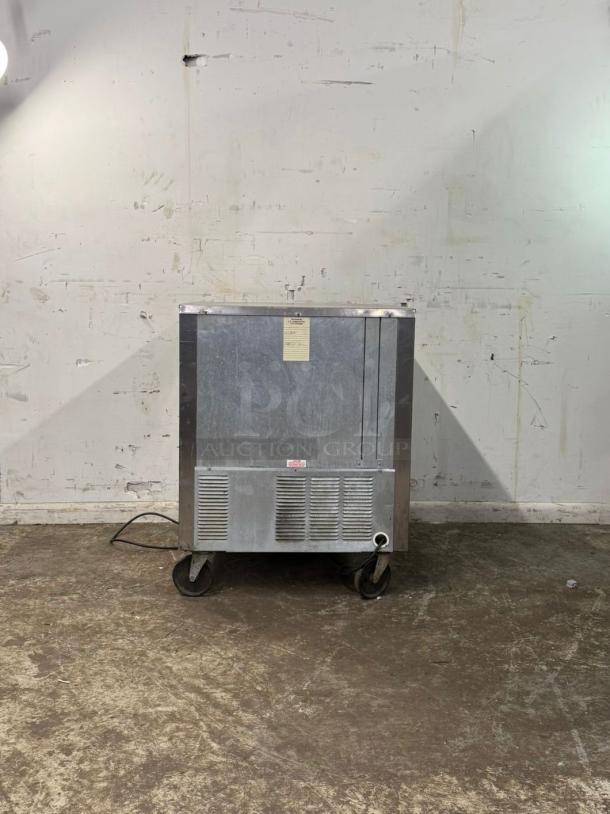 UNDER COUNTER 28" Refrigerator, stainless steel, on casters, visible wear, utility label on front panel.