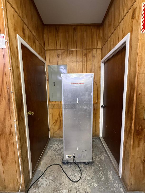 Full-size insulated proofer/warming cabinet, metal exterior, on wheels, plug visible. Marked "Caution: Hot Surface." Good condition.