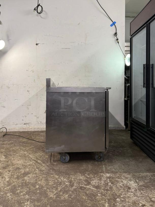Traulsen UHT60-LR undercounter refrigerator, 60" wide, two sections, visible wear, sturdy metal construction, on wheels.