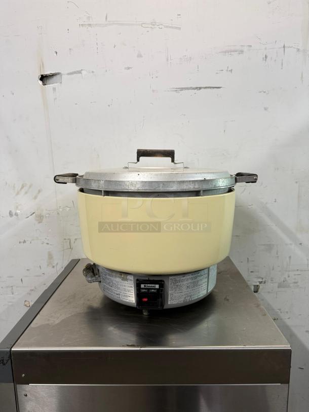 RINNAI 55-cup commercial rice cooker model RER55ASN, natural gas, on metal stand. Visible Rinnai label, good condition.