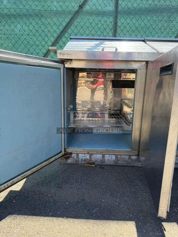 Delfield Model 4472M-30M-A1 72in stainless steel 3-door mega top refrigerated sandwich prep unit; open door view showing interior shelving.