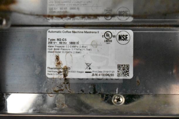 Thermoplan Mastrena M2-CS espresso machine label, showing model, voltage (208V), UL and NSF certification, made in Switzerland.