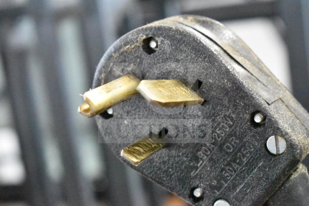 Close-up of a 208-volt power plug for a 2019 Thermoplan Mastrena M2-CS espresso machine. Brass prongs visible.