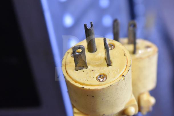 Yellow electrical plug with "20A 125V" markings, showing prongs and visible wear. Designed for high-power connections.