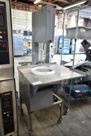 Commercial floor-style meat saw on casters, stainless steel table, used condition, visible brand marking: Groen control unit.