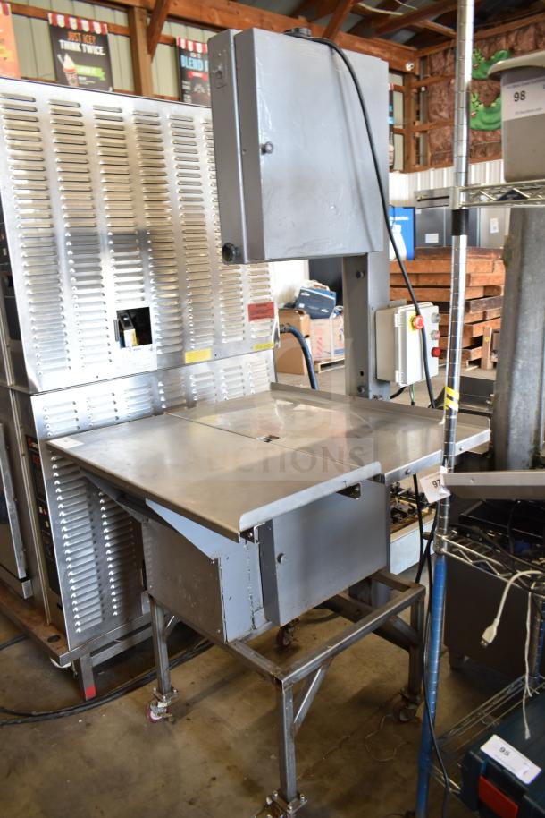 Commercial floor-style meat saw on casters, stainless steel, sturdy design, good condition, includes safety features.