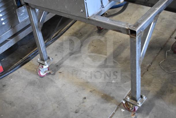 Commercial floor-style meat saw on casters, showcasing sturdy metal frame and wheels. Ideal for heavy-duty use.