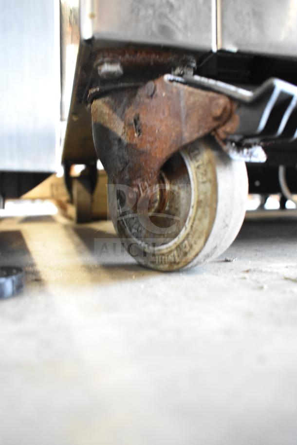 Close-up of the commercial caster wheel of a Koch Ultravac UV500 vacuum sealing machine, showing visible wear and rust.