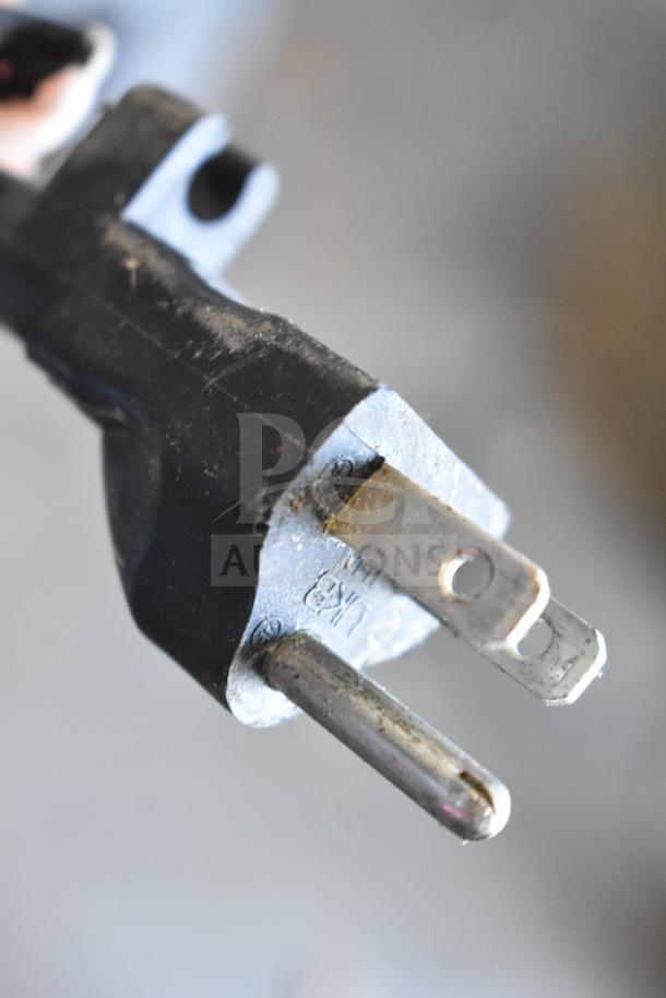 Power plug of Porter & Cable C2002 air compressor, close-up. 120 volts, visible wear on metal prongs, single-phase.