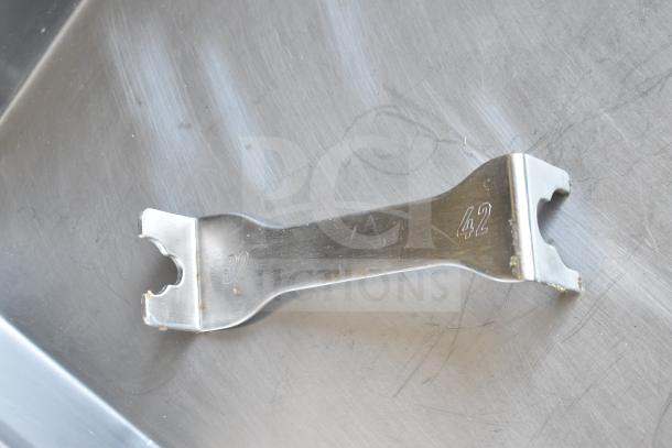 Metal wrench for Minerva Omega A/32 meat grinder, inscribed with "32" and "42" on a stainless steel surface.