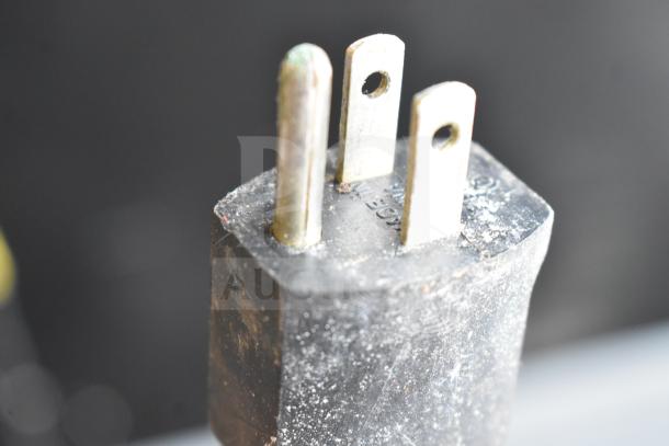 Close-up of a three-prong plug from a Globe 685 Commercial Meat Slicer, showing wear and electrical markings.