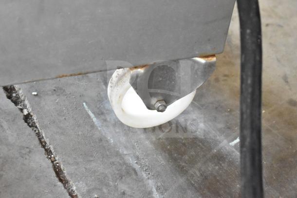 Sirman TC 42 MONTANA electric meat grinder wheel close-up, showing stainless steel construction and mobility feature.