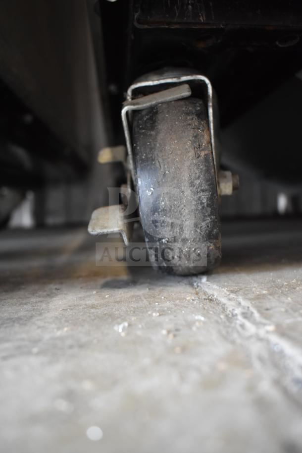 True T-23F commercial freezer caster, showing wear from regular use, on a concrete floor.