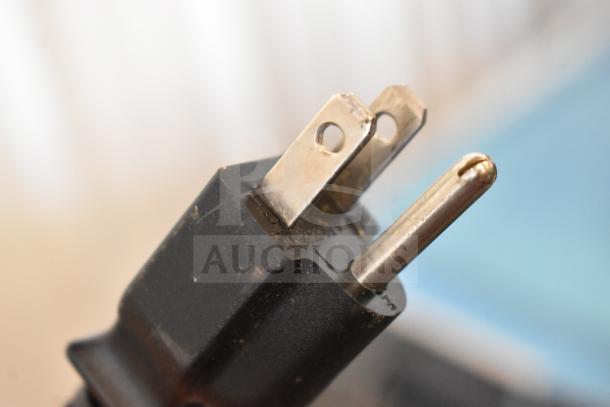 Close-up of black power plug from Hobart HTi-7LH26 Commercial Scale, showing two flat prongs and one round prong, indicating compatibility with 120/208-240 Volts.