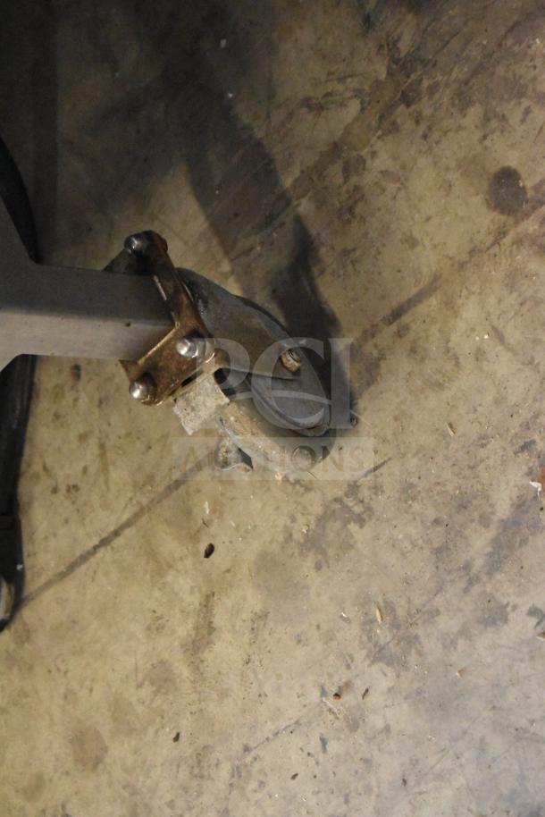 Commercial caster wheel attached to an equipment stand, slightly worn, on a concrete floor. Part of Turbochef HhC2020 setup.