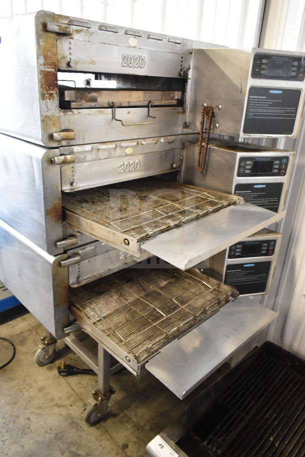 Three Turbochef HhC2020 commercial ovens on stand with casters, showing control panels and conveyor belts, indicating heavy use.