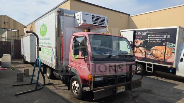 UD International Reefer Box Truck with Thermo King unit, pink cab, exterior signage, appears in used condition, parked outdoors.