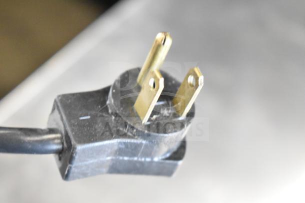 Close-up of a power plug for the Delfield 406P-STAR2 undercounter cooler. The plug has three prongs and a black casing.