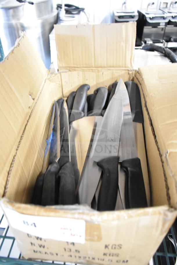 Box of sharpened stainless steel chef knives with black handles. Contains 50 knives, new condition, various models visible.
