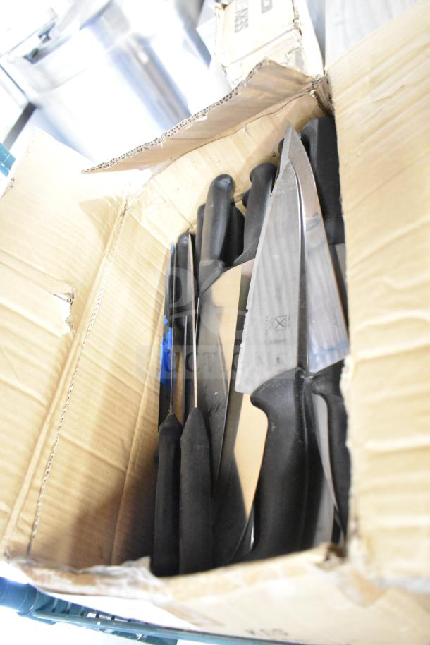 Box of 50 sharpened stainless steel chef knives with black handles, ready for use.