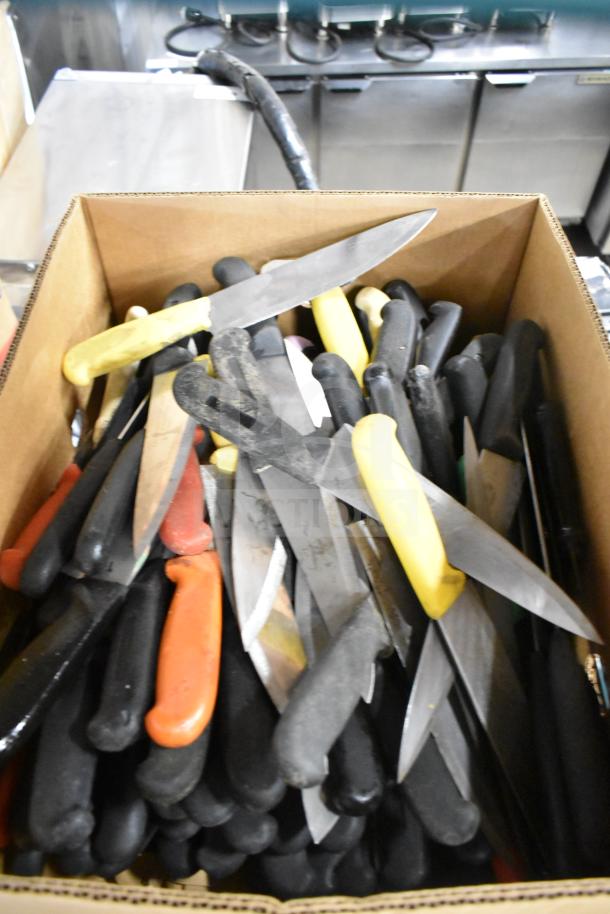 Box of 100 sharpened stainless steel chef knives with assorted colorful handles, ideal for culinary use.