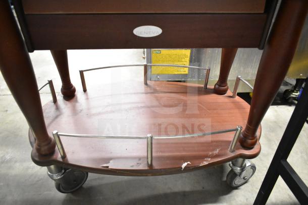 Geneva wooden table with under shelf, metal rail, and commercial casters. Visible Geneva logo tag, slight wear on bottom shelf.