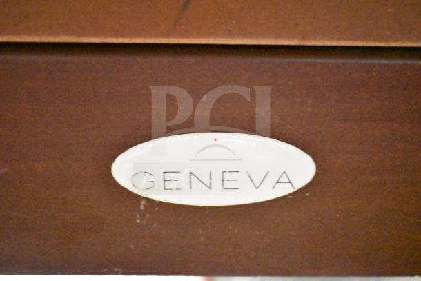 Geneva wooden table with under shelf, commercial casters, Geneva label visible, rich brown finish, good condition.