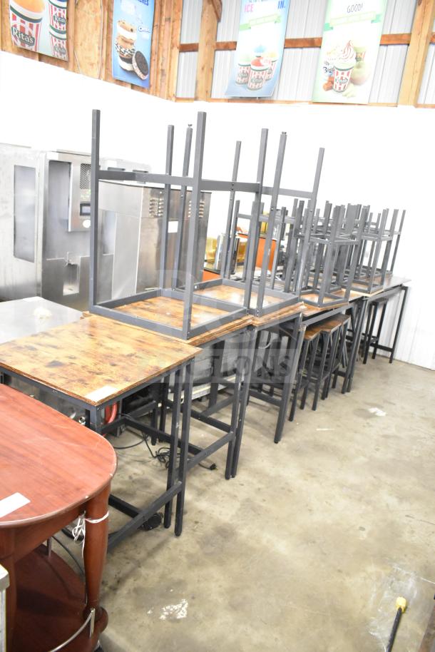 24 wood pattern tables and bar height stools with black metal frames, stacked. Good condition. Auction lot of 24.