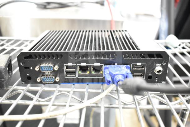 Thin Client Mini PC with VGA, USB, and Ethernet ports, black casing, on metal shelving. Includes Kitchen Armor Monitor.