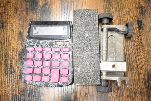 Lot includes a floral Staples calculator, a gray poly bus bin, and a metal clamp, all in used condition.