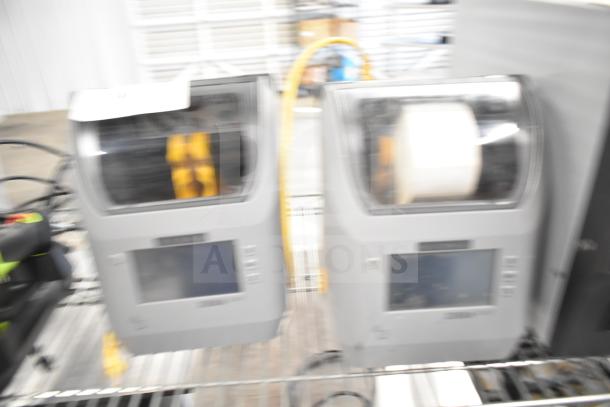 Two Zebra ZD621 desktop direct thermal barcode printers on a metal shelf. Visible LCD screens, moderate condition.