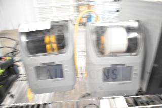 Two Zebra ZD621 desktop direct thermal barcode printers on a metal shelf. Visible LCD screens, moderate condition.