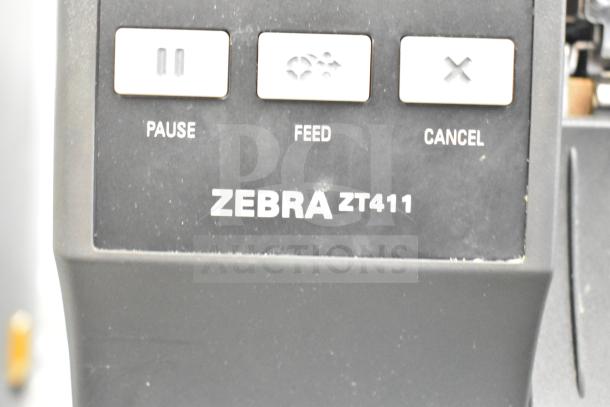 Zebra ZT411 Industrial Barcode Printer in black, with visible "PAUSE," "FEED," and "CANCEL" buttons; model branding shown.