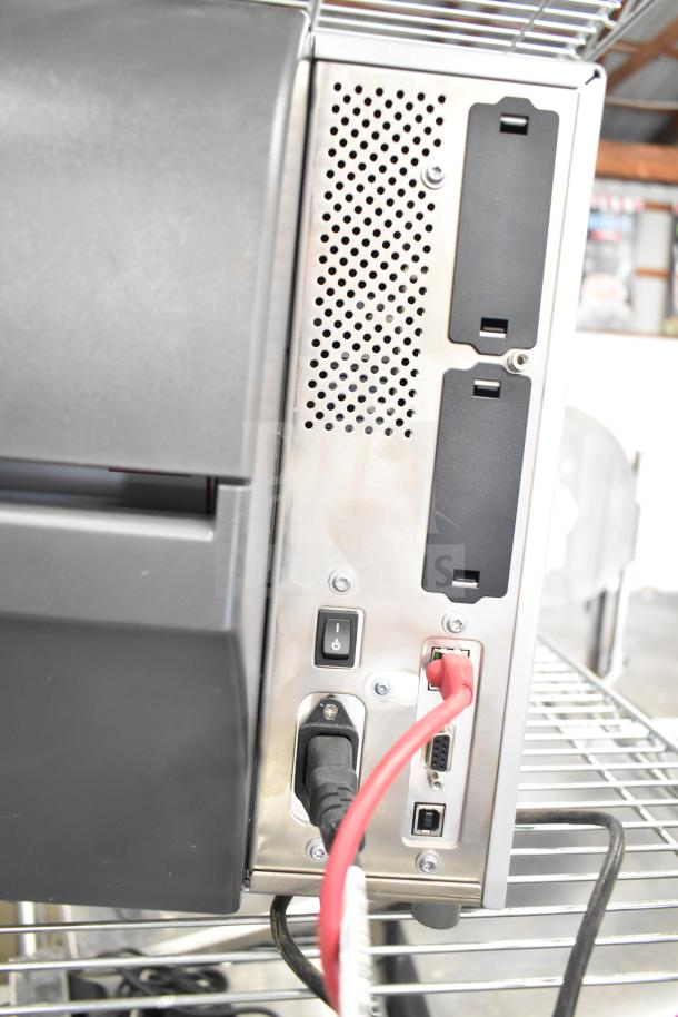 Zebra ZT411 Industrial Barcode Printer, back view, showing ports and power connections, metal casing, good condition.