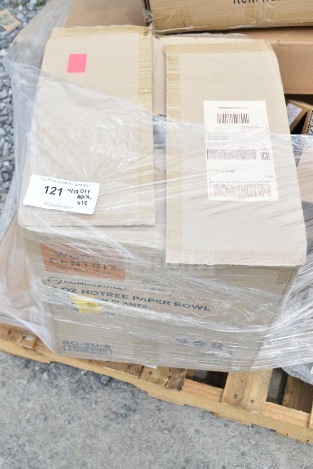 Cardboard boxes of assorted brand new scratch and dent items on a pallet, wrapped in plastic. Labels show item codes and auction details.