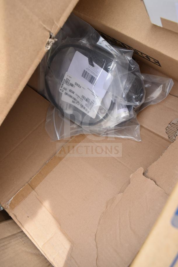 Box with new scratch and dent items, including a mobile desk, shelving unit, and light. Labels visible with codes.