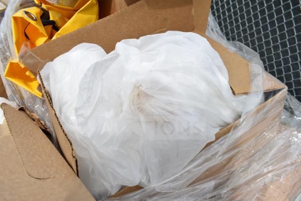 Cardboard box containing assorted scratch and dent items, including yellow fabric and white plastic, wrapped in plastic.