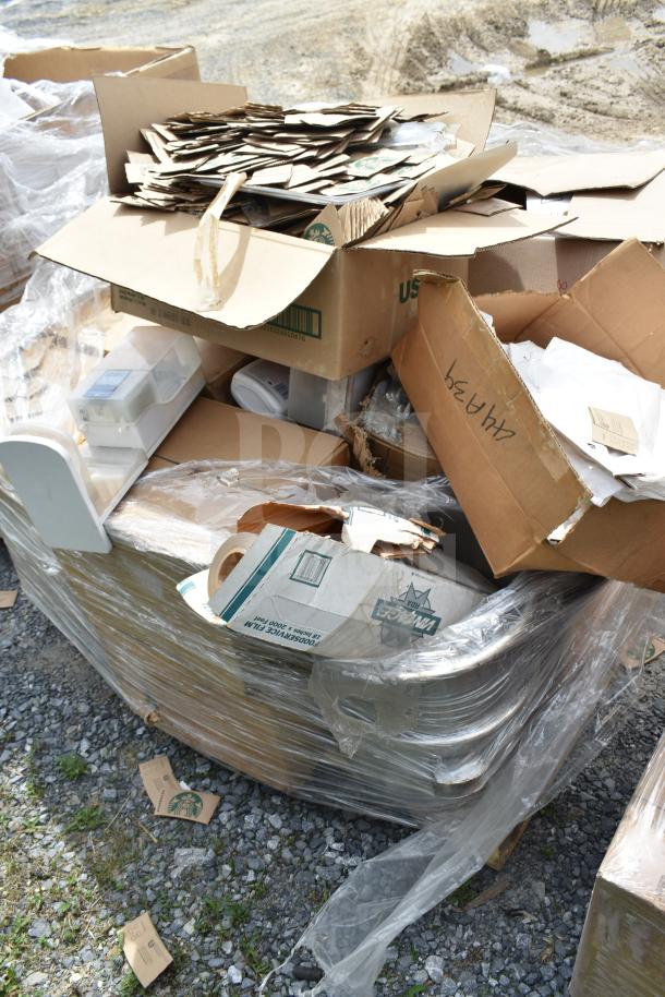 Box of brand new scratch and dent items including hot cup sleeves and retail boxes, wrapped in plastic.