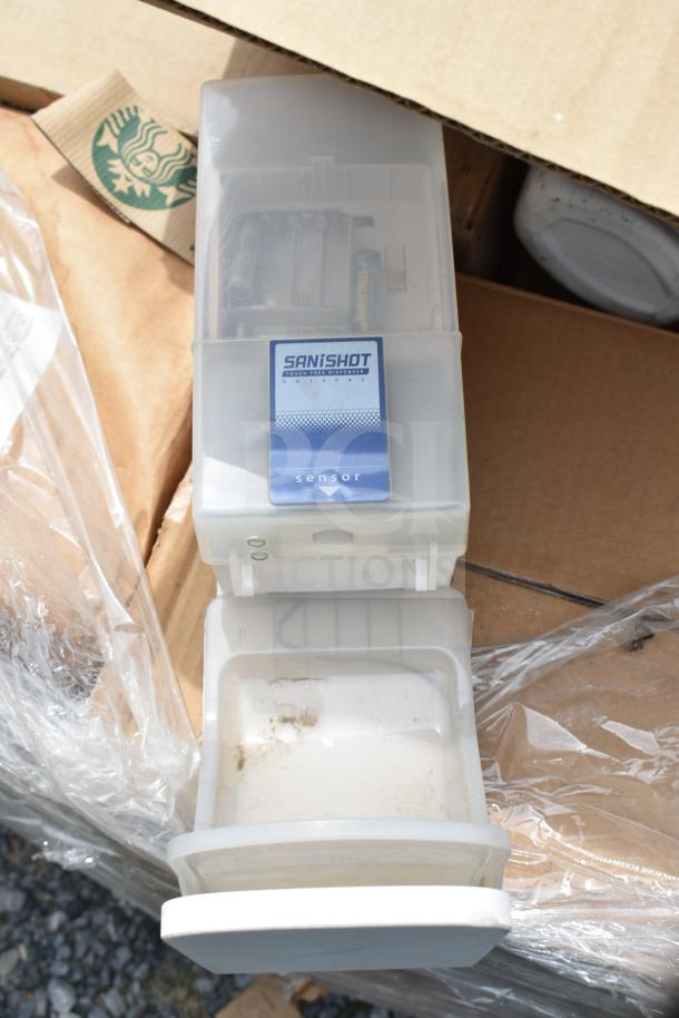 SanisShot touch-free dispenser in white plastic, partially open, showing some wear. Includes branded packaging.