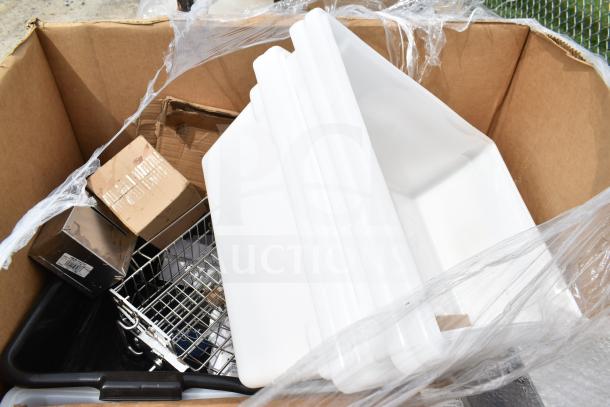 Cardboard box with assorted new scratch and dent items, including white trays, metal racks, and packaged goods.