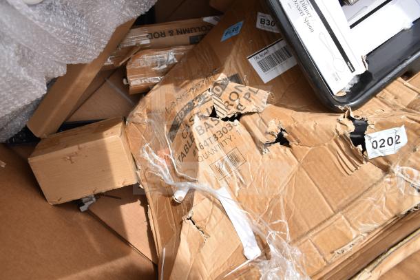 Damaged boxes containing scratch and dent items, including a work table and speed rail. Visible labels show item codes and details.