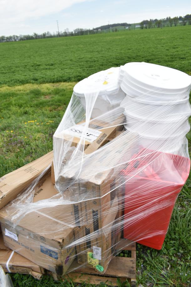 A pallet of 16 brand new scratch and dent items including white trash cans and red seat cushions, wrapped in plastic.