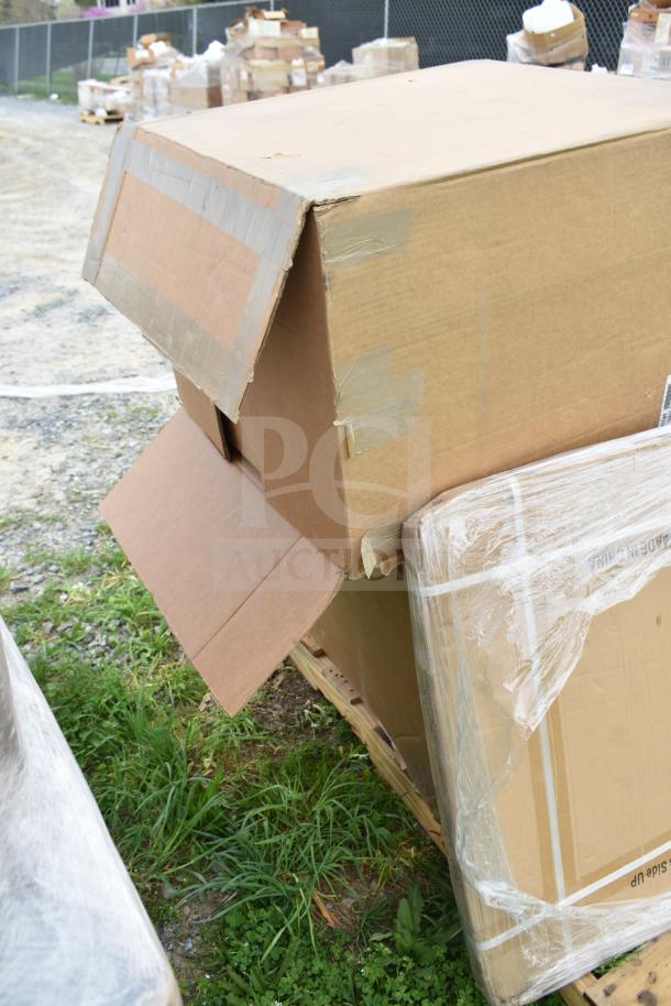 Cardboard boxes containing scratch and dent items, including a bakery display case and VitaMix blender, visibly taped and slightly open.
