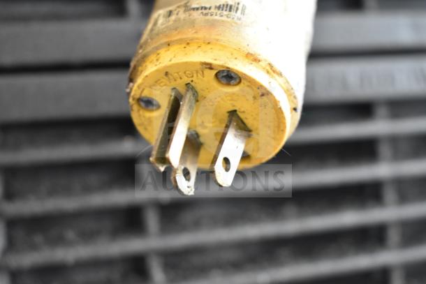 Alt text: Close-up of a yellow electrical plug showing three prongs labeled "Leviton 15A-125V" with visible dirt and wear.